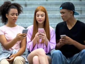 three teenagers browsing on phones
